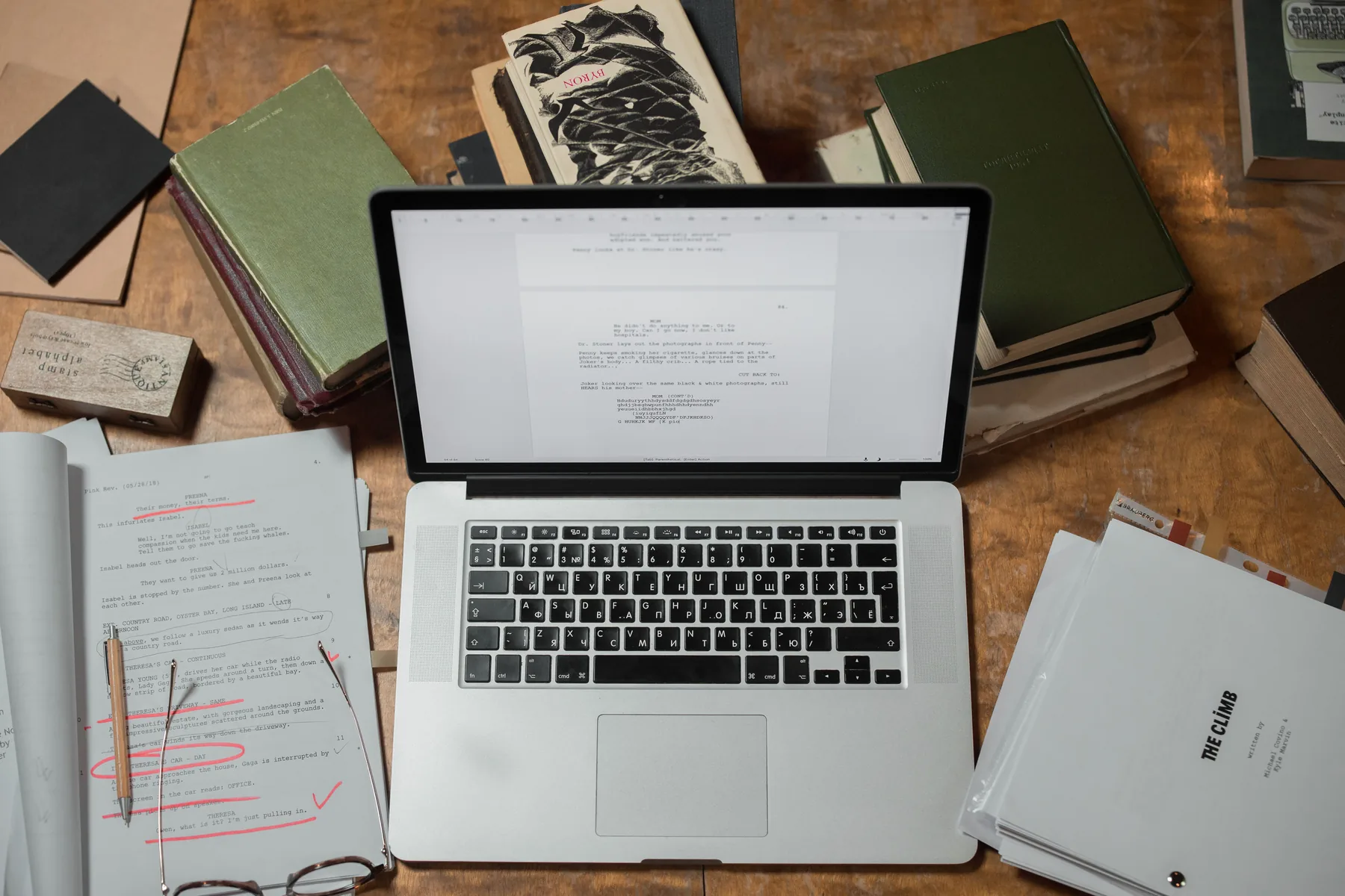 Writing studio workspace with laptop, manuscripts, and books